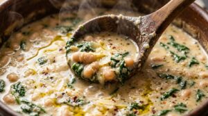 Ultra close-up macro of ladle scooping simmering creamy Tuscan white bean and spinach soup with garlic cream broth and grated parmesan