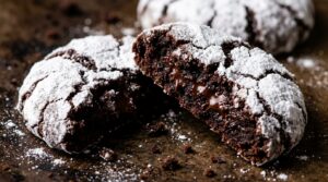 Ultra close-up macro of fudgy chocolate crinkle cookie broken in half showing molten brownie center and snowy powdered sugar cracks