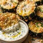 Ultra close-up macro food photography of golden crispy baked zucchini rounds crusted with panko and parmesan