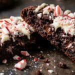 Ultra close-up macro of fudgy dark chocolate peppermint bark cookie with melted white chocolate drizzle and crushed candy canes